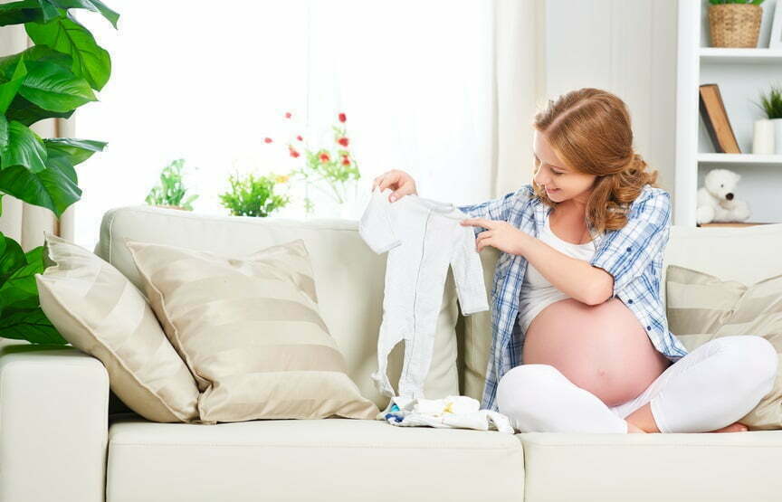 Mujer embarazada preparando la ropita para su bebé
